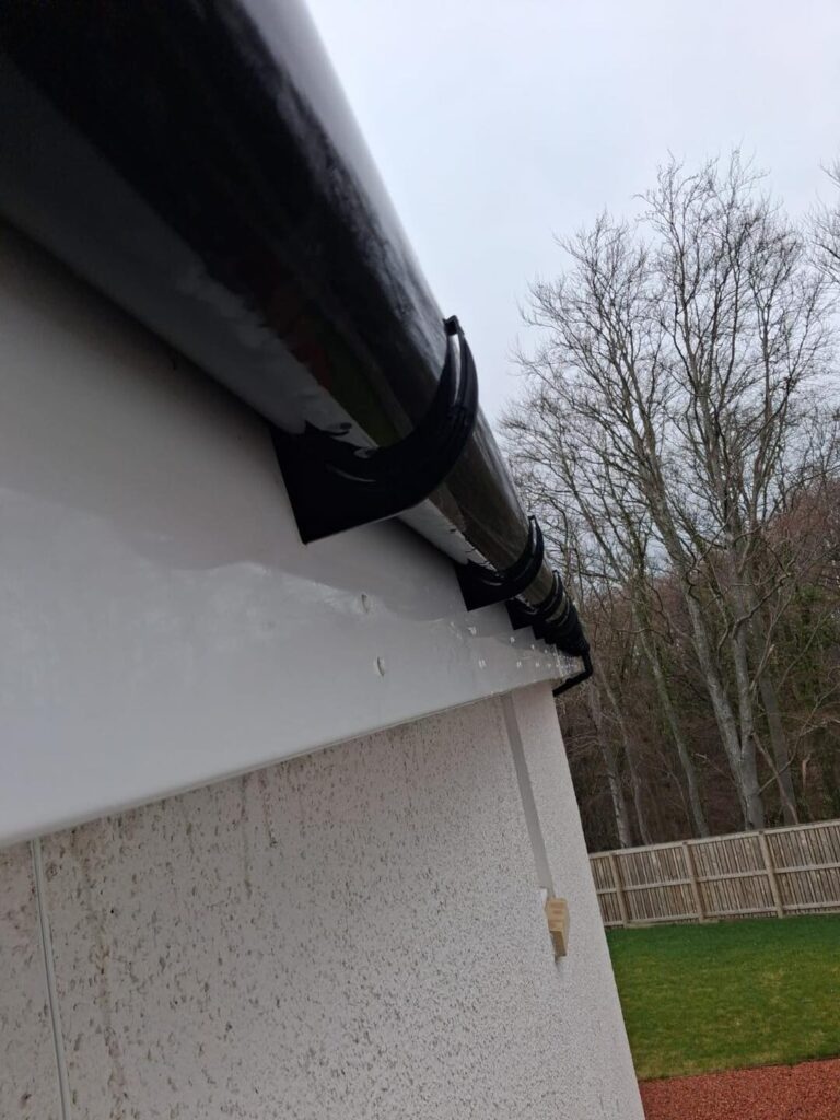 A close-up view of black plastic guttering and fascia boards following a cleaning service
