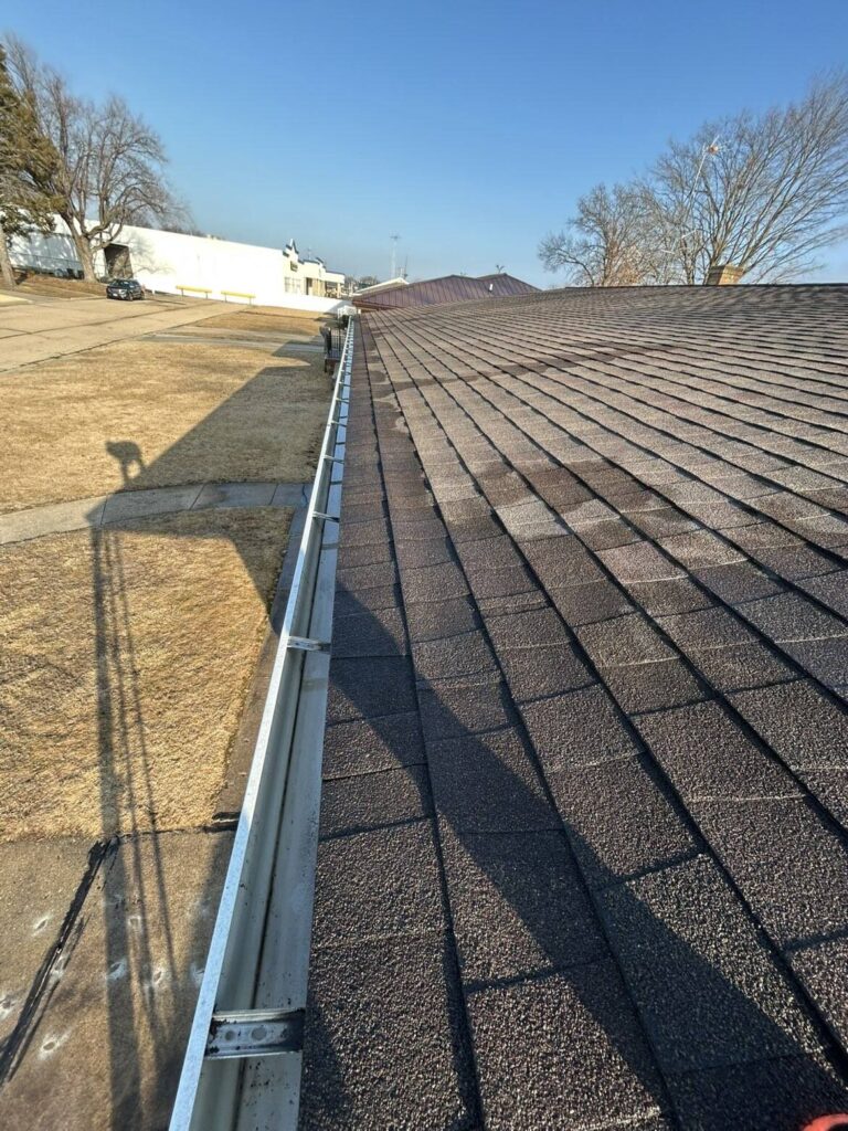 A view of a clear, debris-free gutter system on a residential roof, showcasing a successful cleaning and maintenance service.