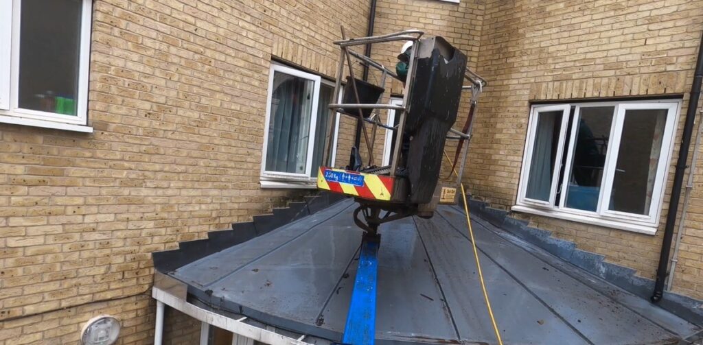 Professional team using an aerial lift platform to perform commercial gutter cleaning and maintenance on a multi-story building exterior.